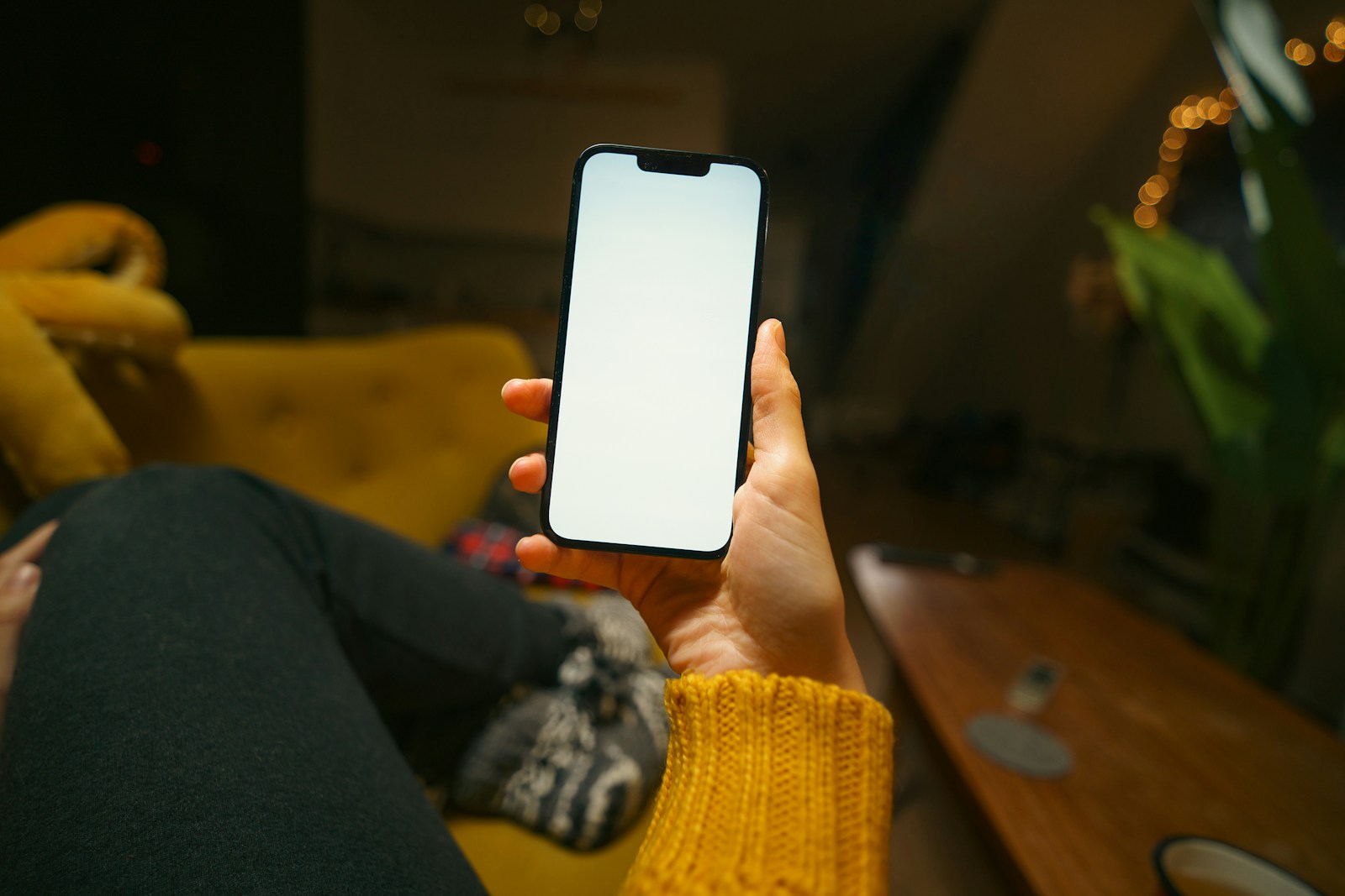 ソファでくつろぎながら、片手でスマートフォンを持って画面を見ている手元