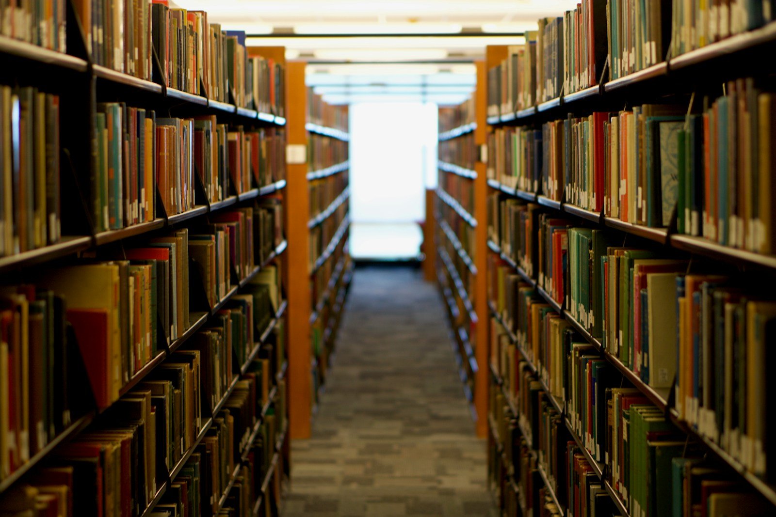 人のいない図書館で、本棚が両側に並ぶ通路